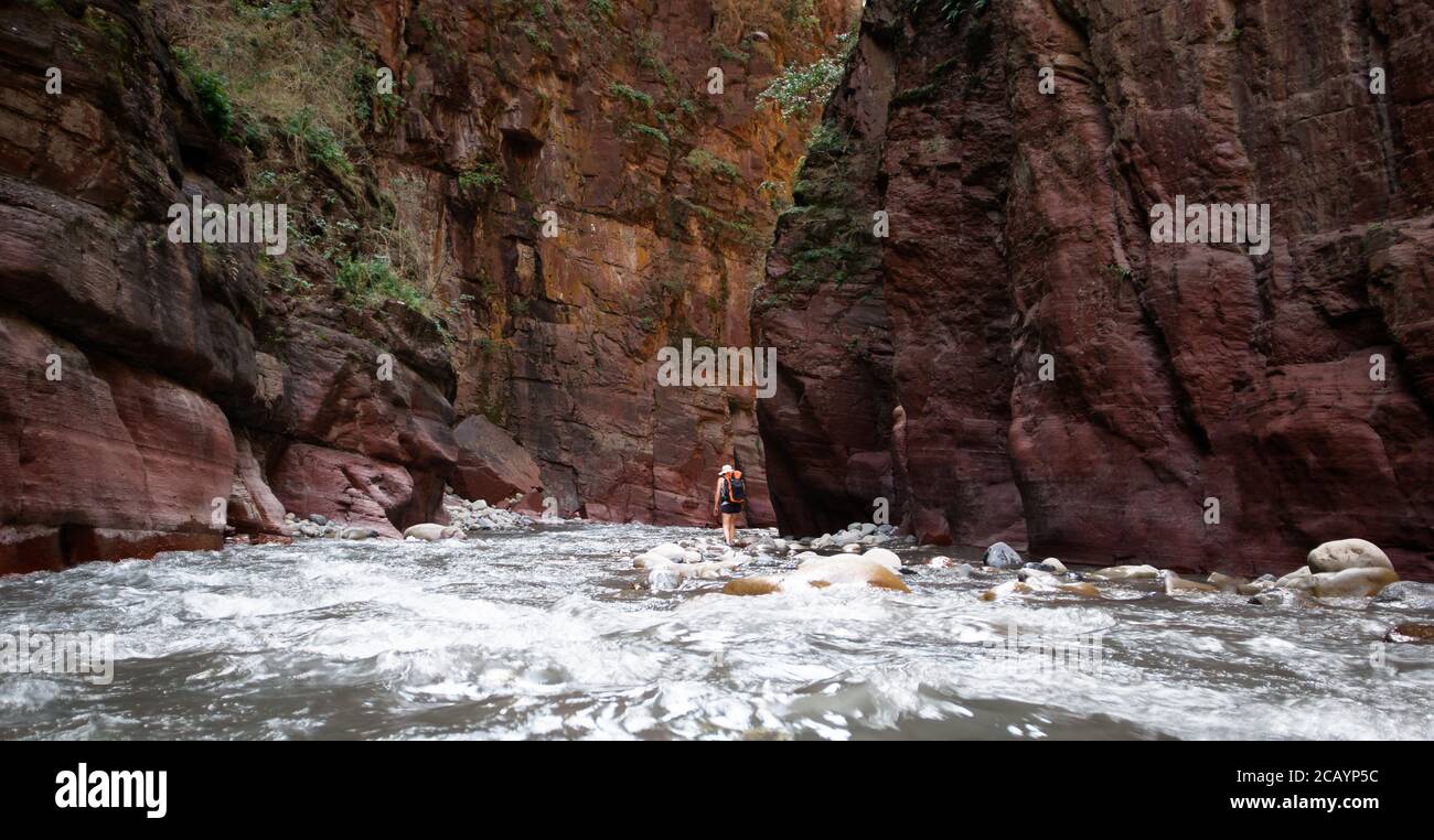 Woman walking Var river between red and orange cliffs at the bottom of Daluis Canyon or Daluis gorge Stock Photo