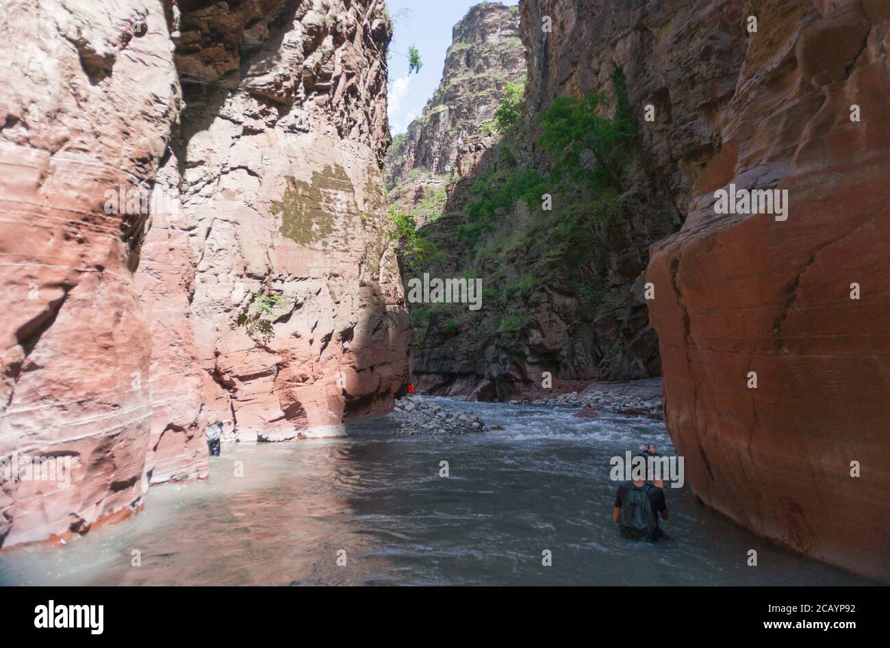 Boy walking Var river between red and orange cliffs at the bottom of Daluis Canyon or Daluis gorge Stock Photo
