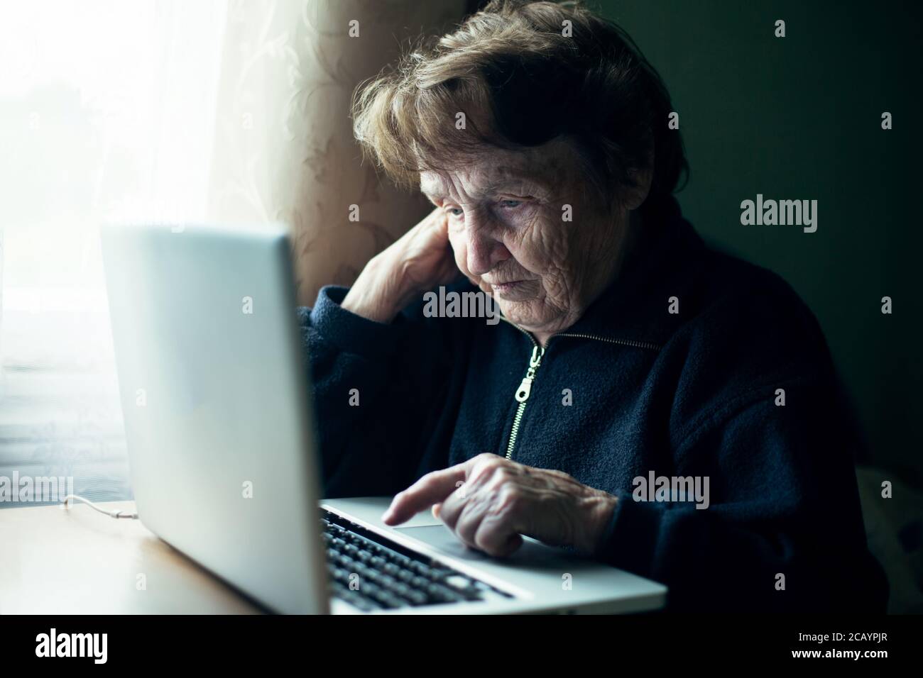 An old russian woman using laptop at home. Stock Photo