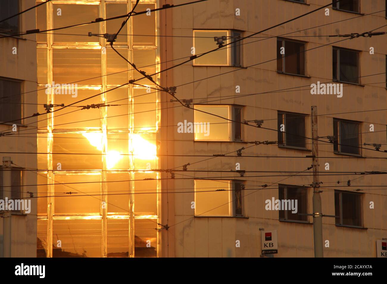 In Palmovka, Prague, Czech Republic, you can see the setting sun's light of yellow/ orange colours being reflected on the building for that bank, KB. Stock Photo