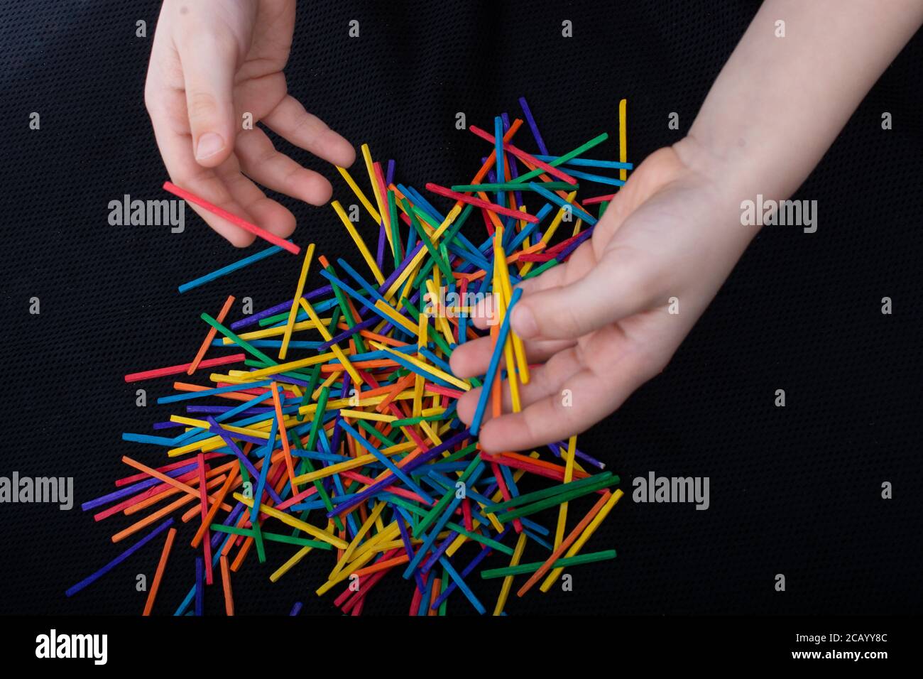 Kid playing with coloured wooden sticks for creativity on white ...