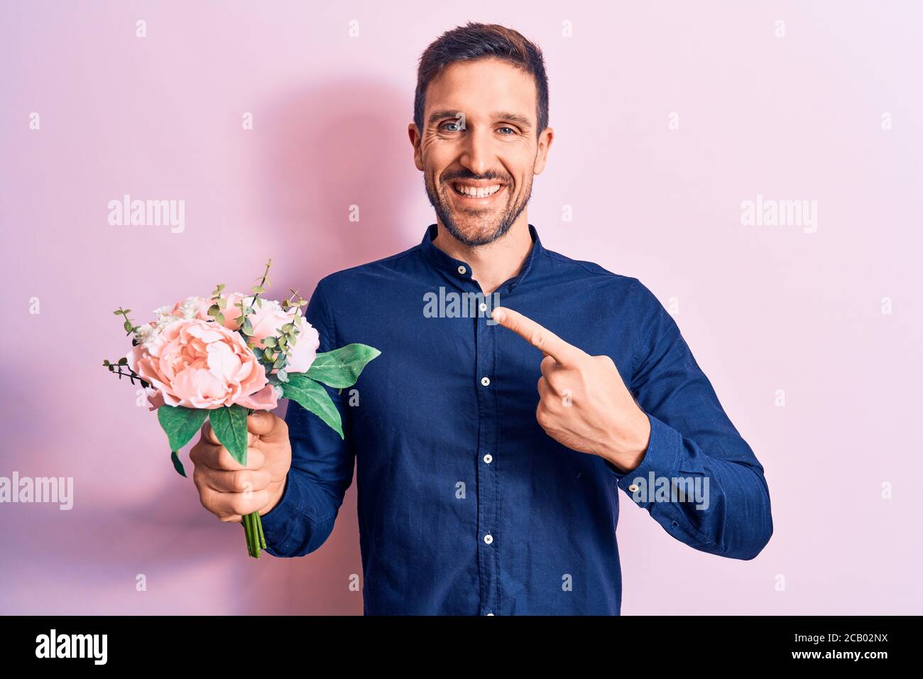 Young handsome romantic man holding beautiful bouquet of flowers over ...