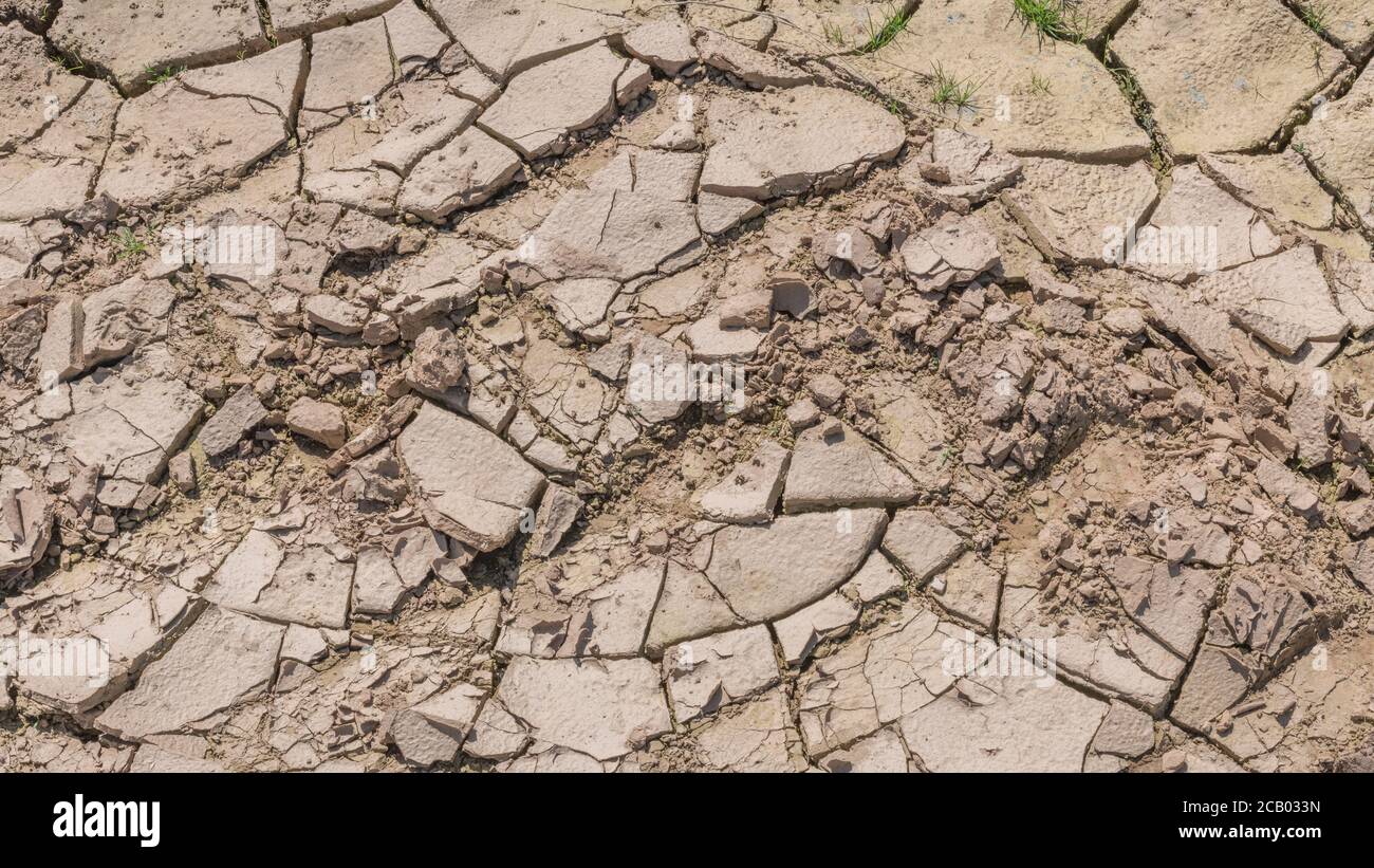 Wide 16:9 Cracked mud in dry field drainage ditch. For water shortage, water crisis, heatwave, heatwave crops, gardening in heatwave, soil science Stock Photo
