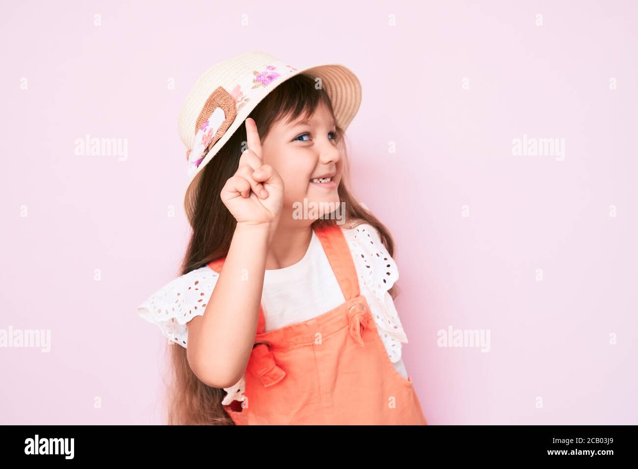 Little caucasian kid girl with long hair wearing spring hat smiling ...