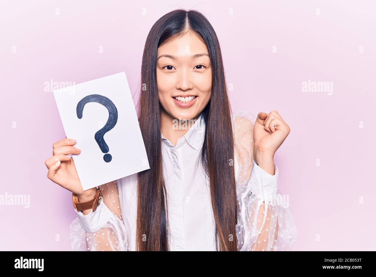 Young beautiful chinese woman holding question mark screaming proud ...