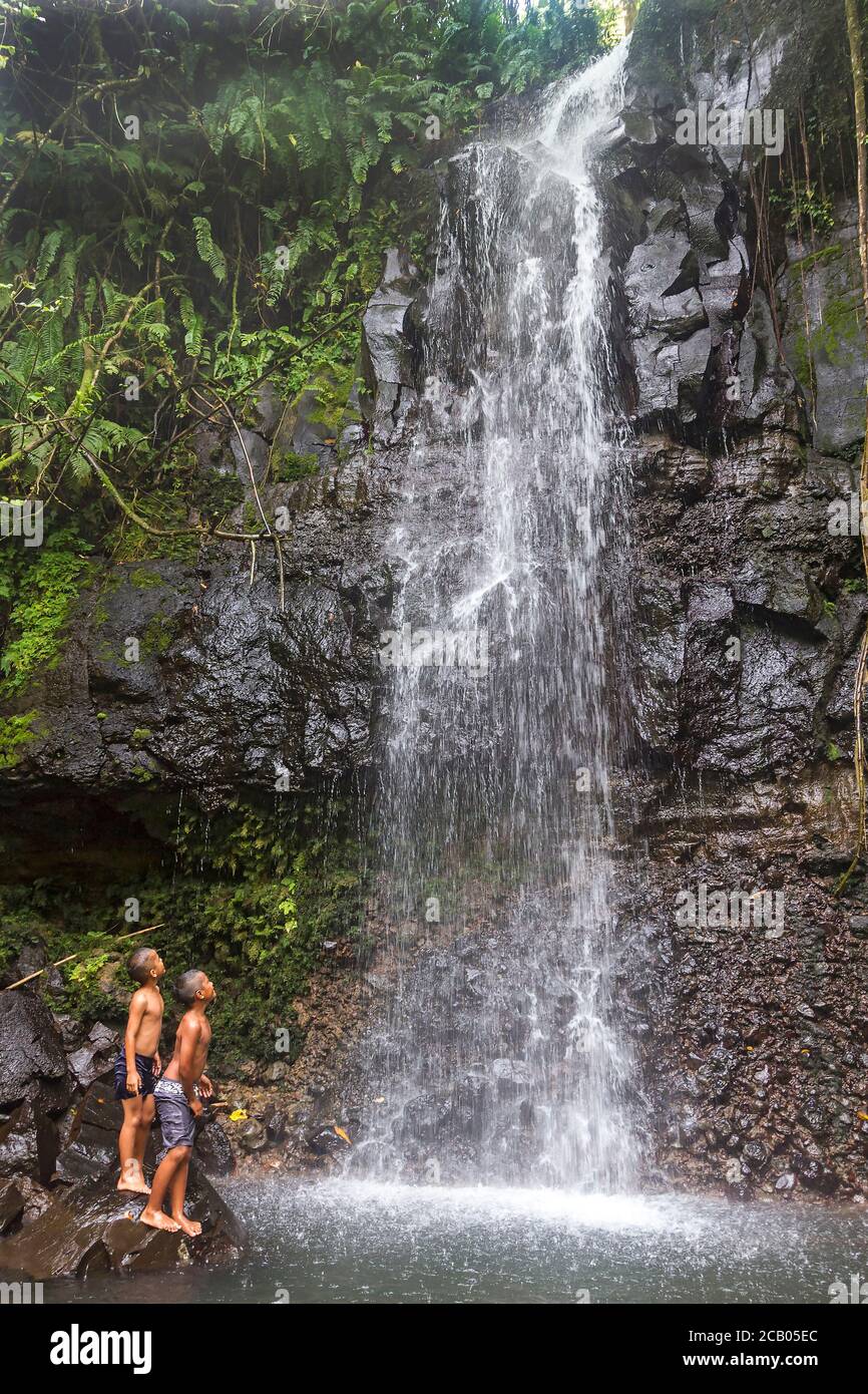 Young native boys play in cascading spray of Sipyen Waterfall, Kosrae,  Micronesia. Stock Photo