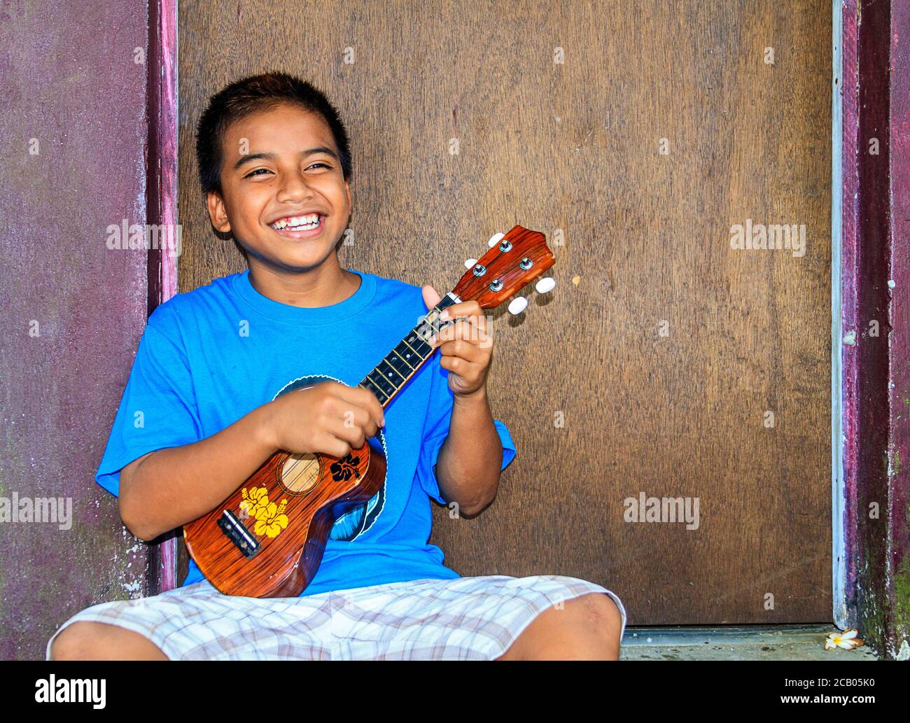 Local boy plays his ukulele. The ukulele is a popular musical instrument on Kosrae, Micronesia, as it is on many Pacific islands. Stock Photo