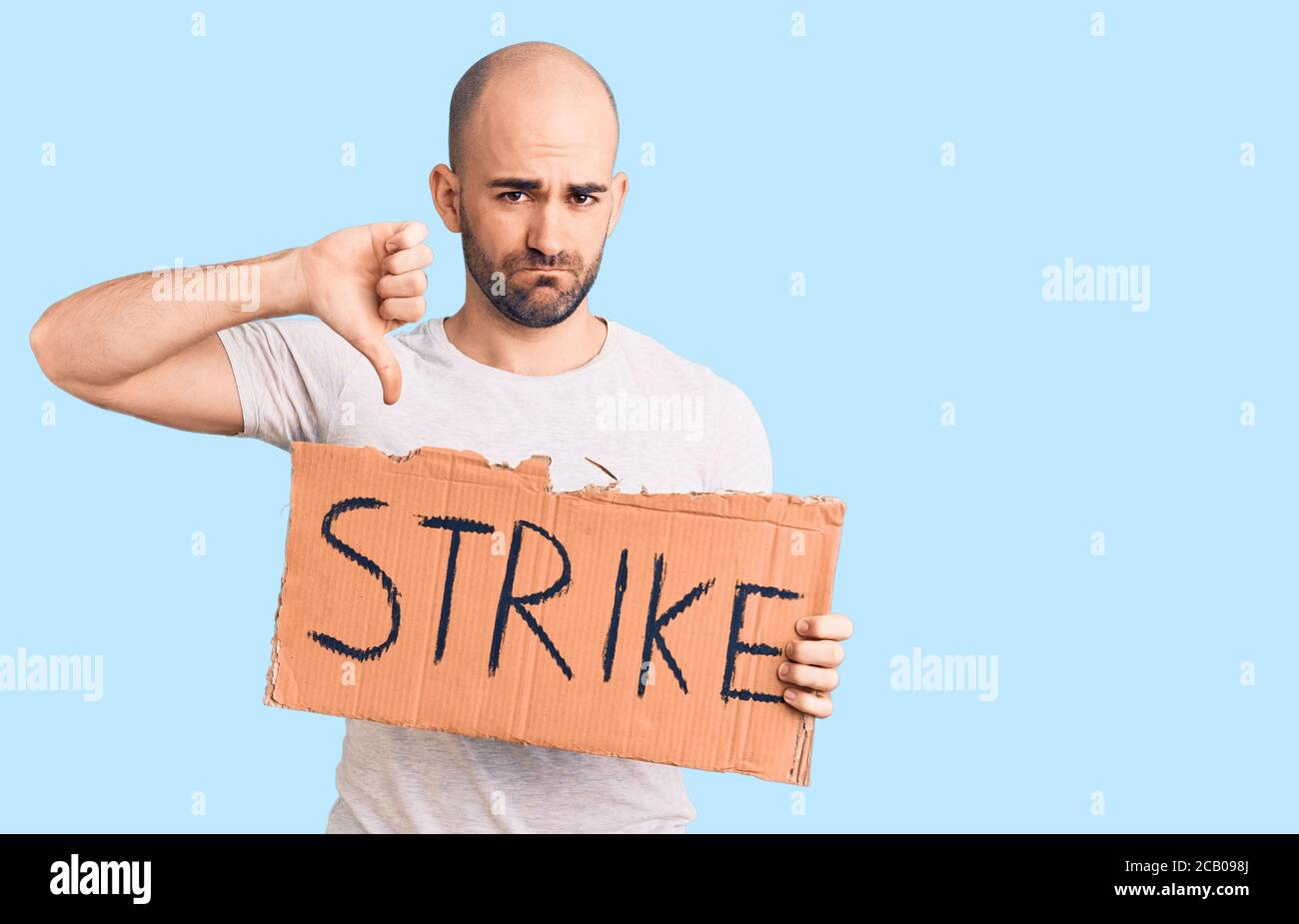 Young handsome man holding strike banner with angry face, negative sign showing dislike with thumbs down, rejection concept Stock Photo