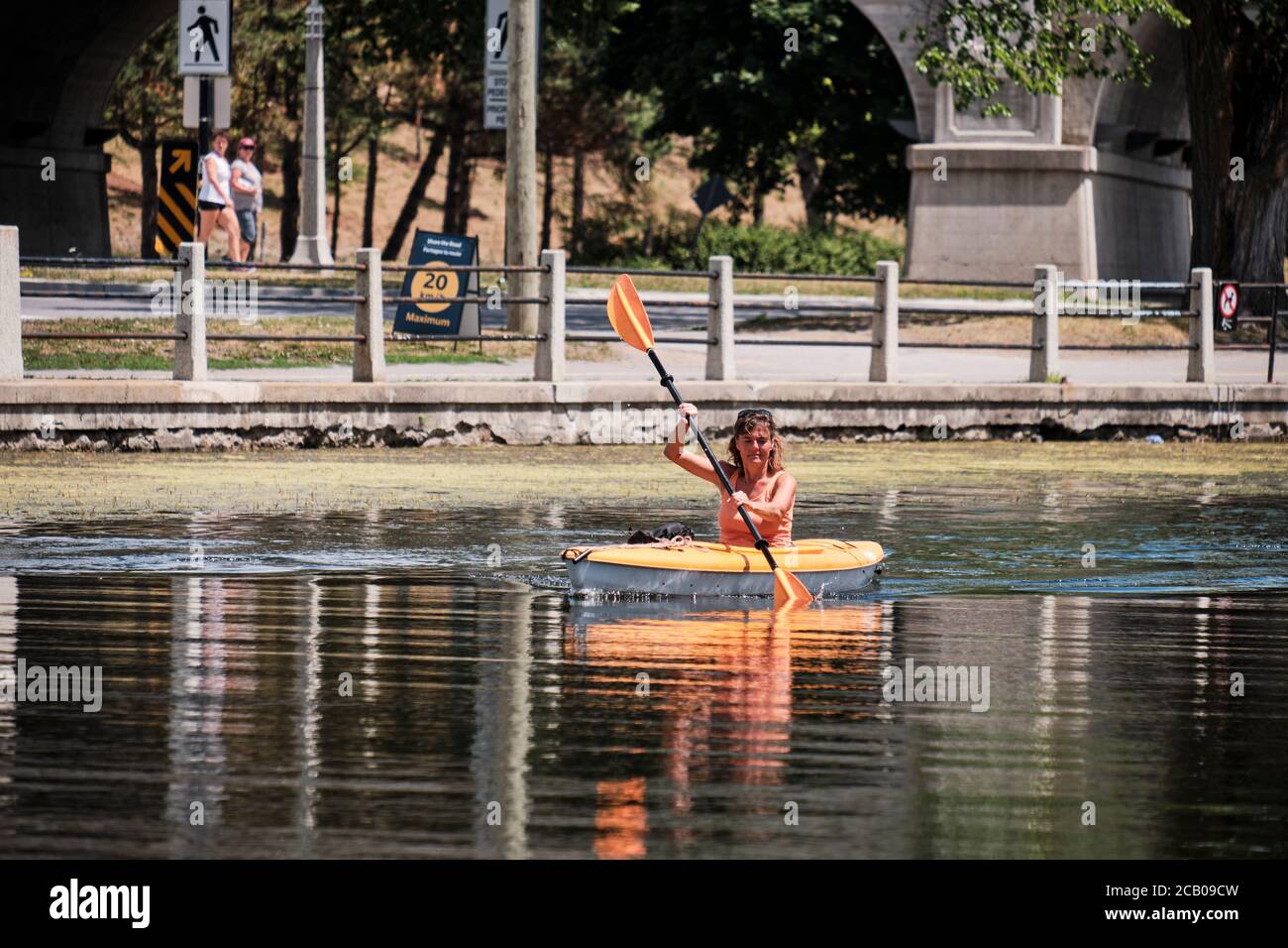 Woman in orange kayak rowing in Rideau Canal water in central Ottawa Stock Photo