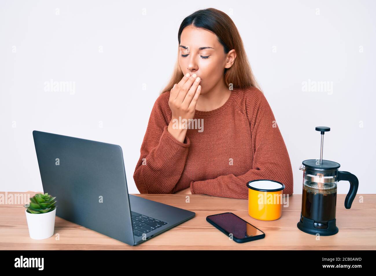 Young woman working at the office drinking a cup of coffee
