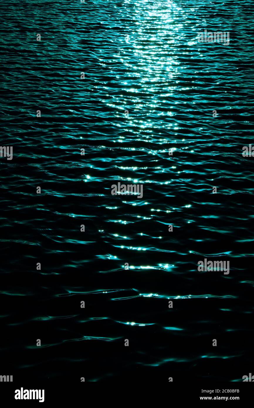 Ripples of water surface with sun reflections, dark tone image with ...