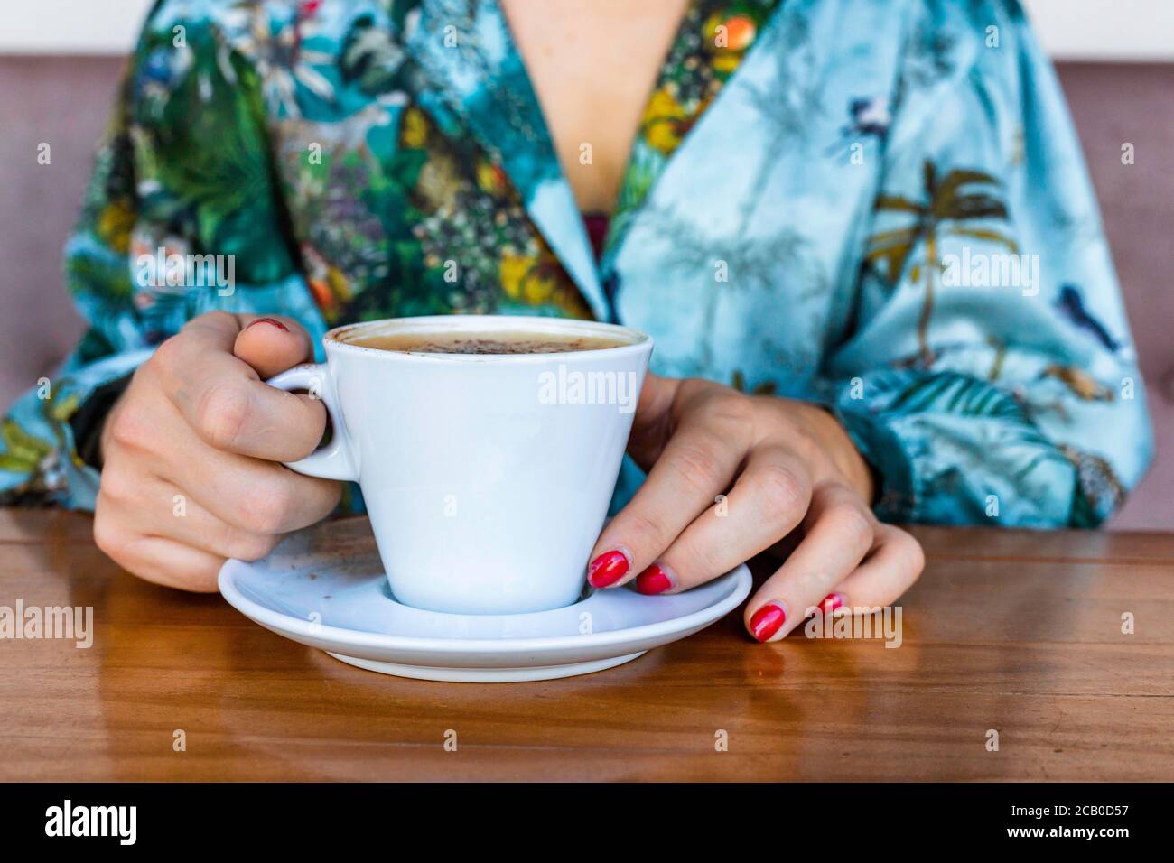 A young beautiful woman drinking a cappuccino all alone in a local coffee shop in the city of Lisbon, Portugal Stock Photo