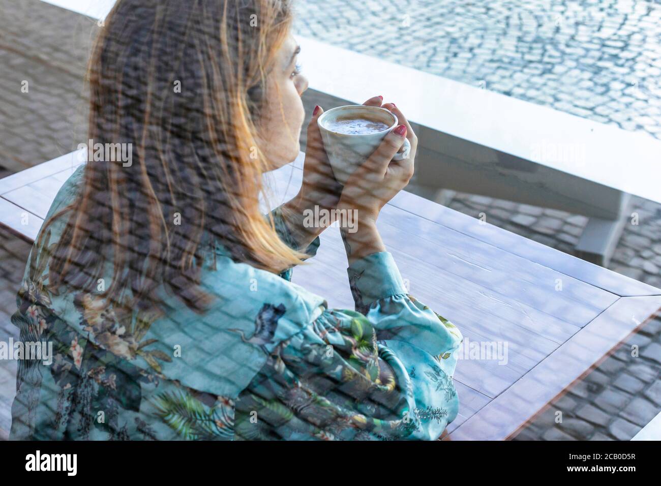 A young beautiful woman drinking a cappuccino all alone in a local coffee shop in the city of Lisbon, Portugal Stock Photo