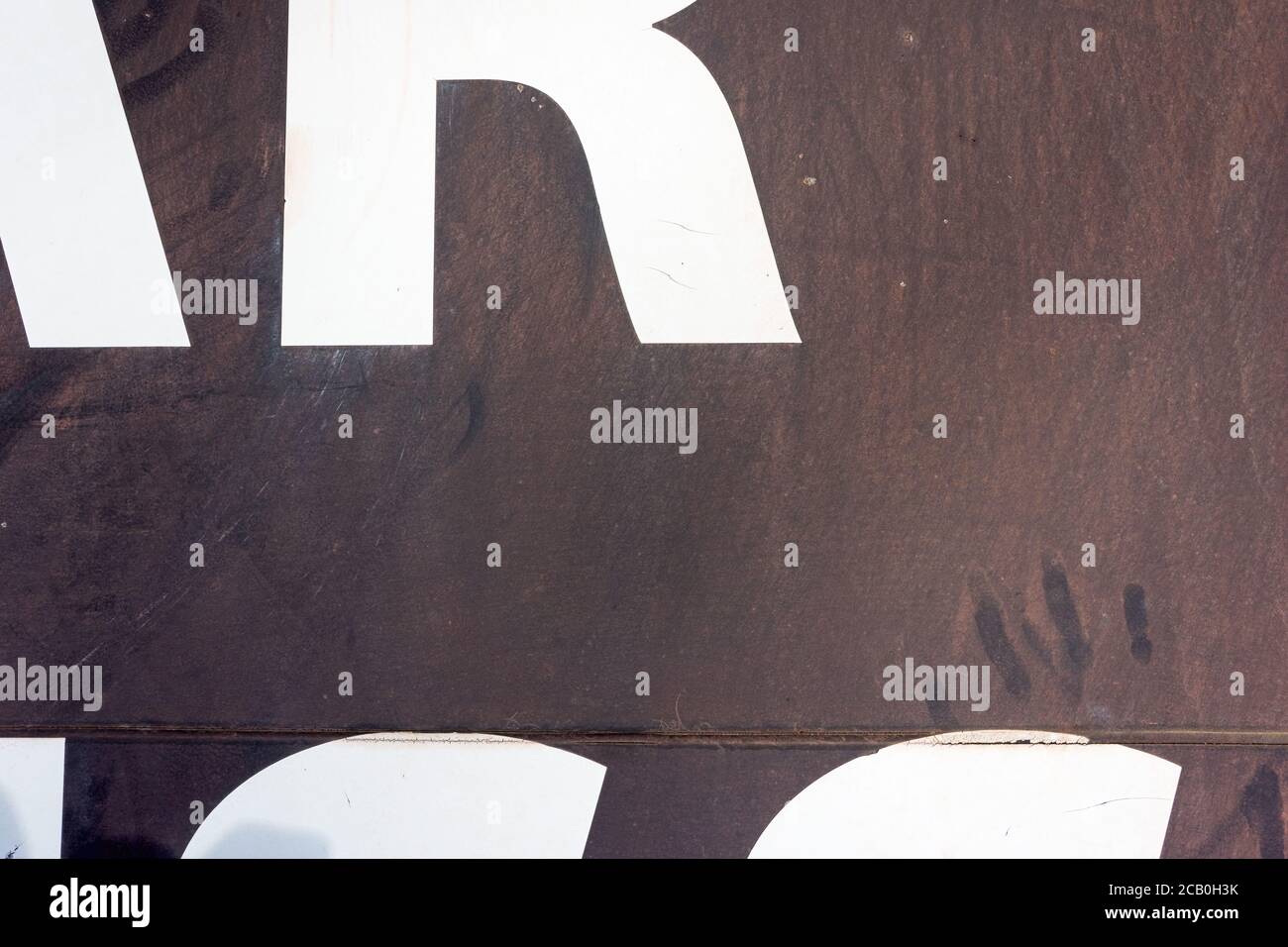 Typography abstract pattern and graphic lettering on a brown metal background with dusty handprint. Stock Photo