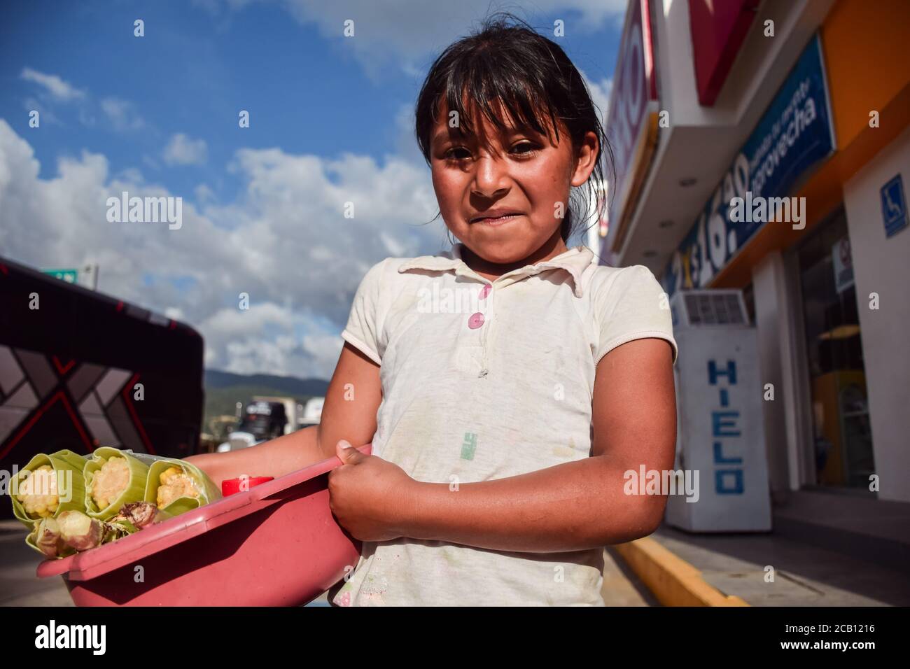 Chiapas / Mexico - September 15, 2016: portrait of little mexican girl selling boiled ears of corn at gas station Stock Photo