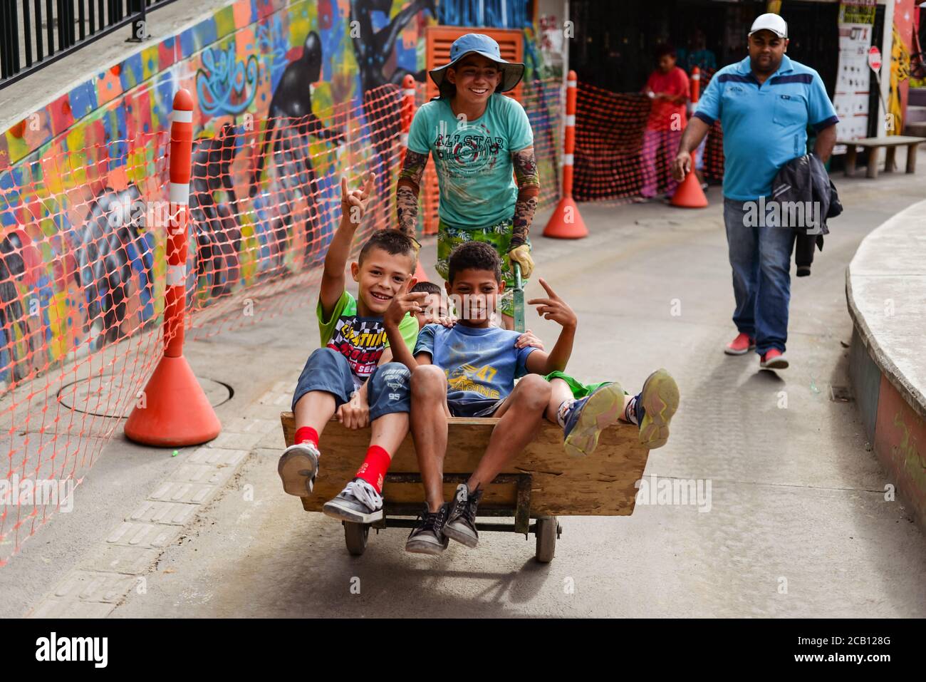 Medellin / Colombia - July 15, 2017: Colombian children playing riding on wheelbarrow in the street Stock Photo