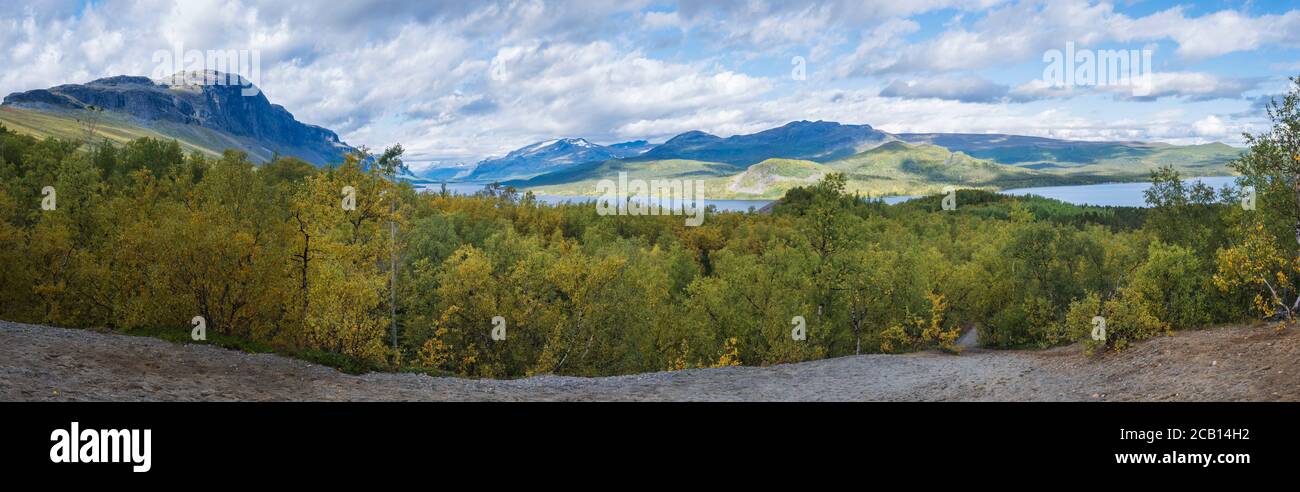 Panoramic landscape with beautiful river Lulealven, snow capped mountain and yellow birch tree. Kungsleden hiking trail near Saltoluokta, north of Stock Photo