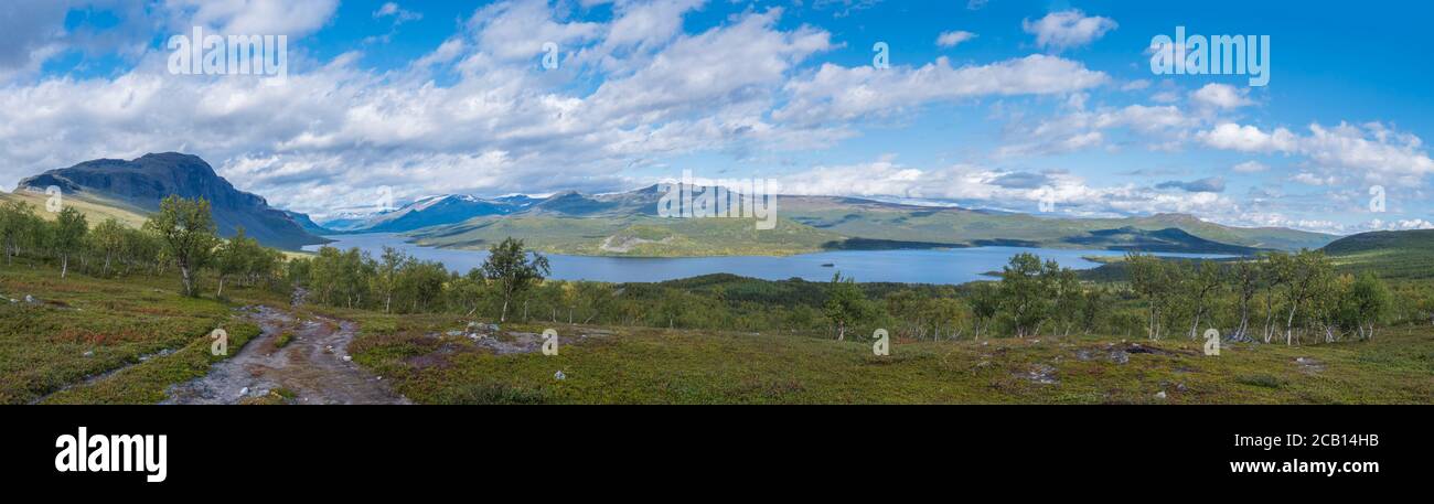 Panoramic landscape with beautiful river Lulealven, snow capped mountain, birch tree and footpath of Kungsleden hiking trail near Saltoluokta, north Stock Photo