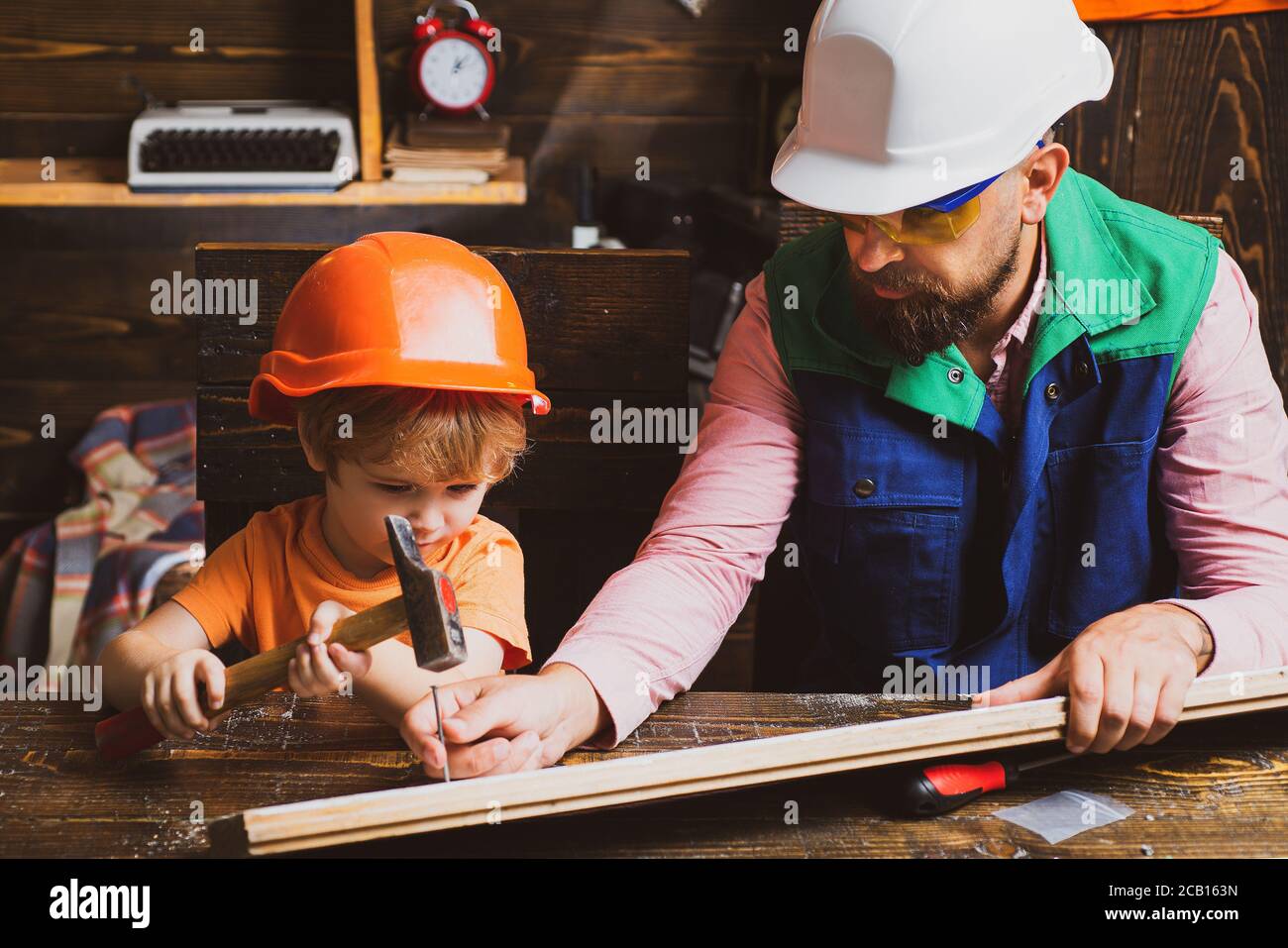 Father and son working with a hammer. Future kids profession. Construction of dad and boy in the garage. Stock Photo