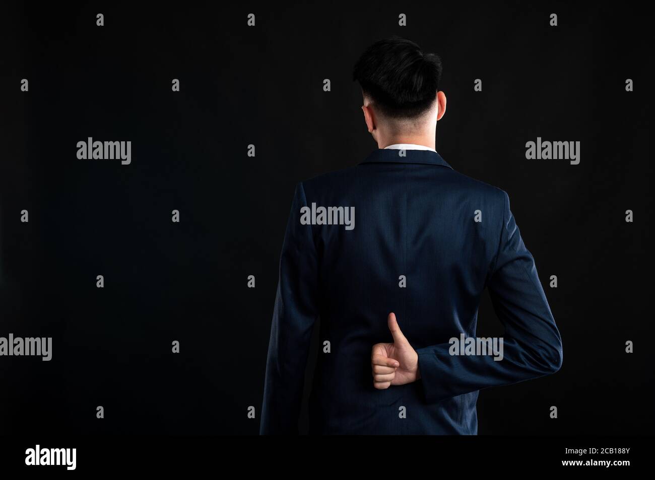 Back view of business man wearing blue business suit and tie thumbs up ...