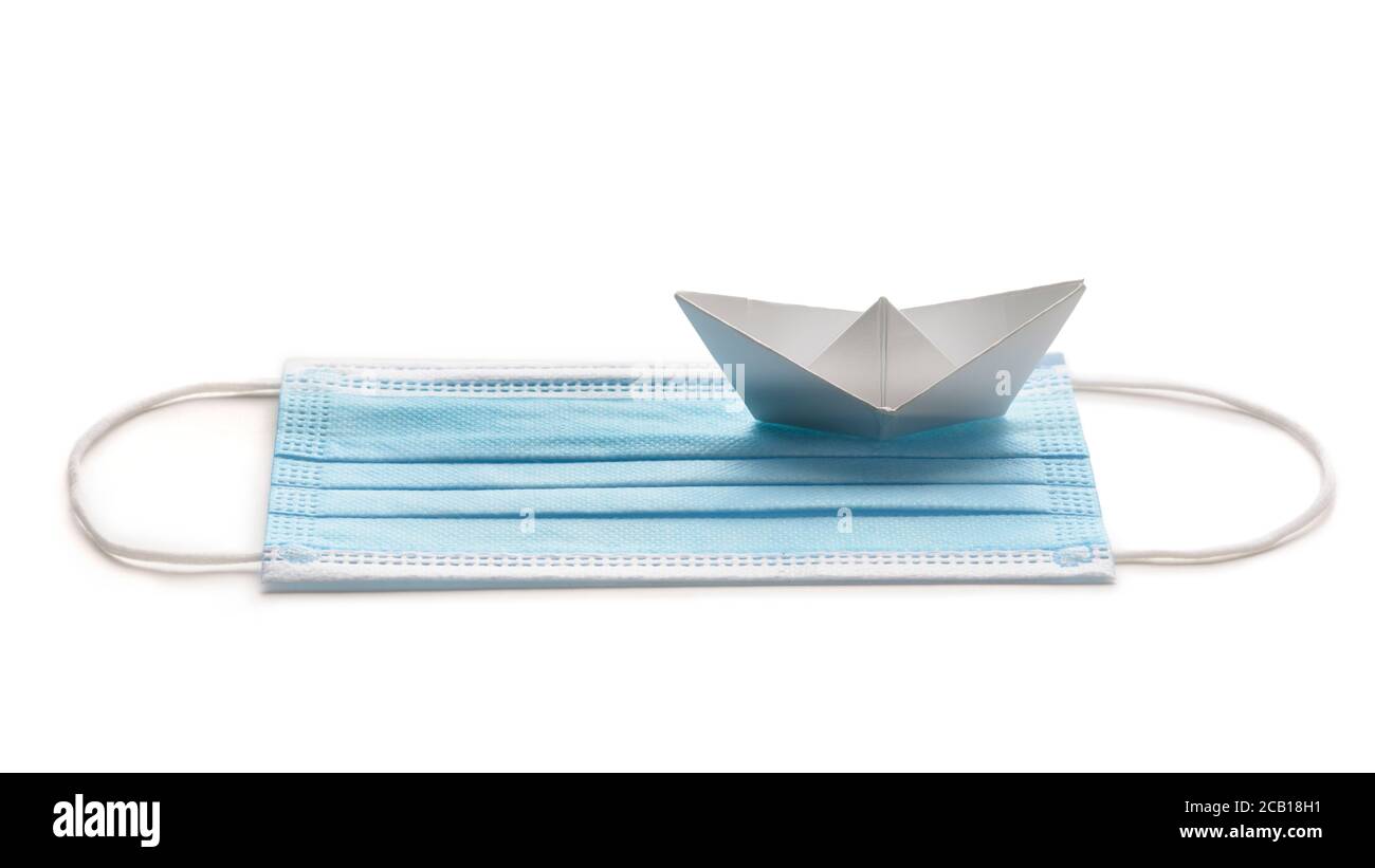 Traveling during pandemic crisis. Surgical mask with white paper ship