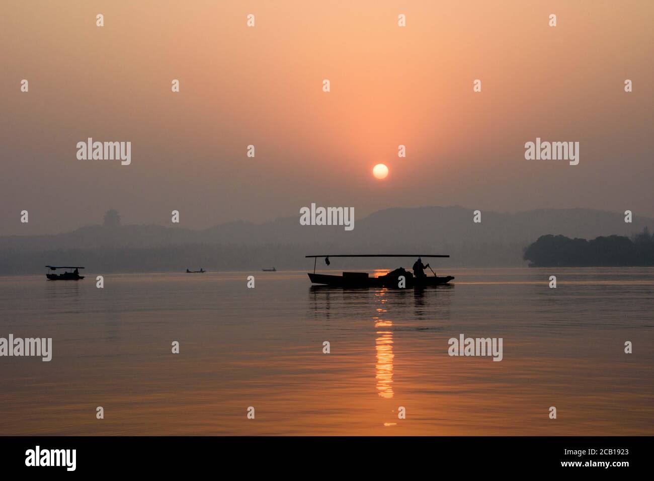 Boats floating on water lake in Hangzhou, China during sunset Stock Photo