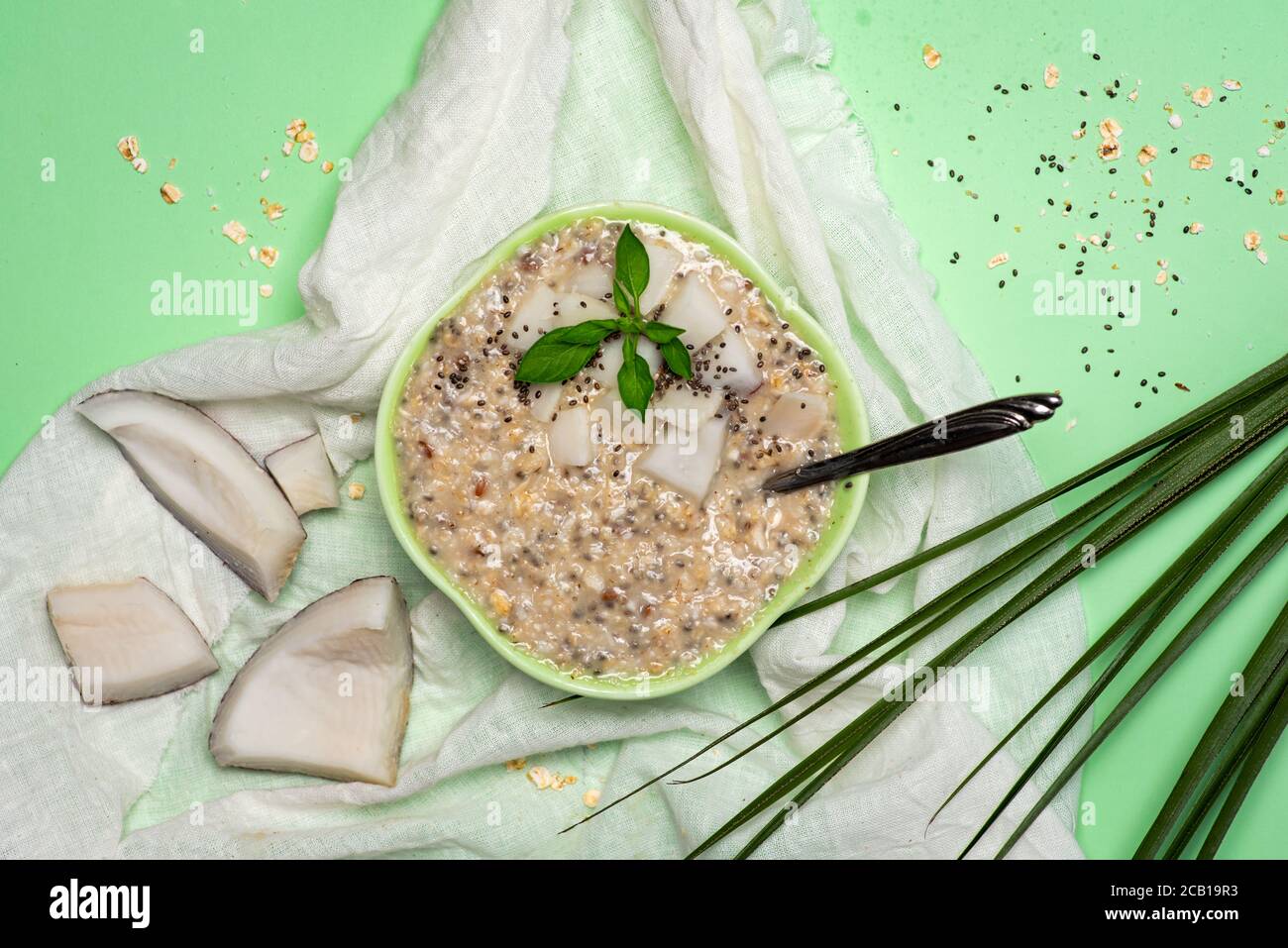 Oatmeal porridge with grated coconut and chia seeds in a green bowl top view Stock Photo