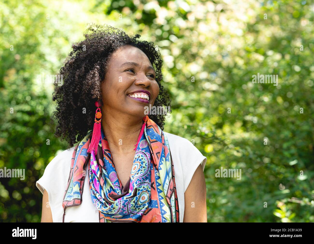 Portrait of a laughing, dark-skinned woman with curly hair and colourful scarf, Germany Stock Photo