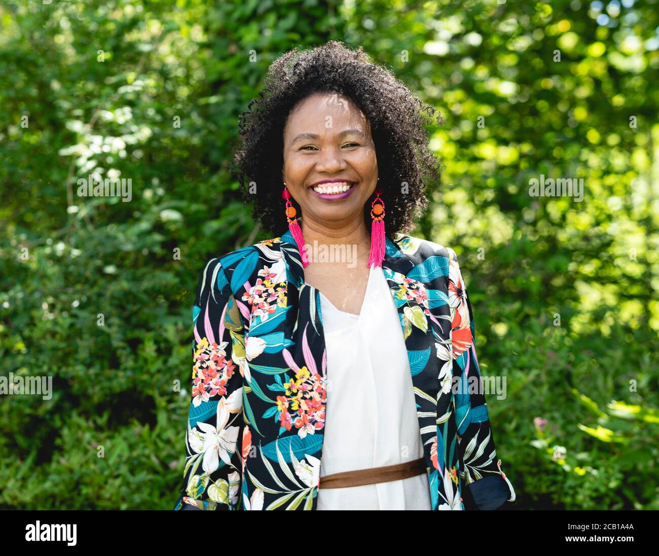 Dark skinned woman with curly hair and colorful jacket hi-res stock