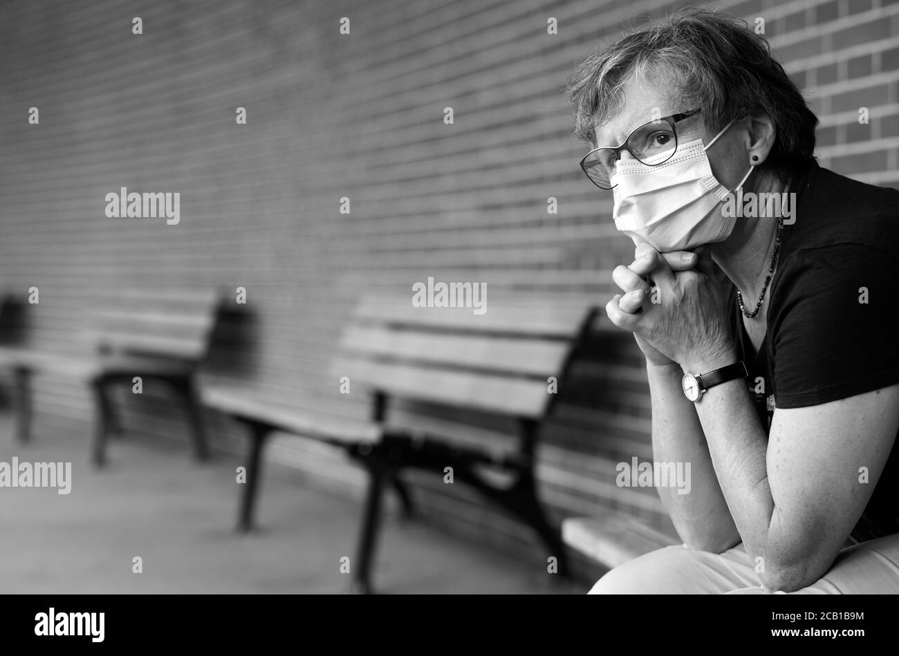 Woman with face mask, sitting on a bench, pensive, Corona crisis, Stuttgart, Baden-Wuerttemberg, Germany Stock Photo