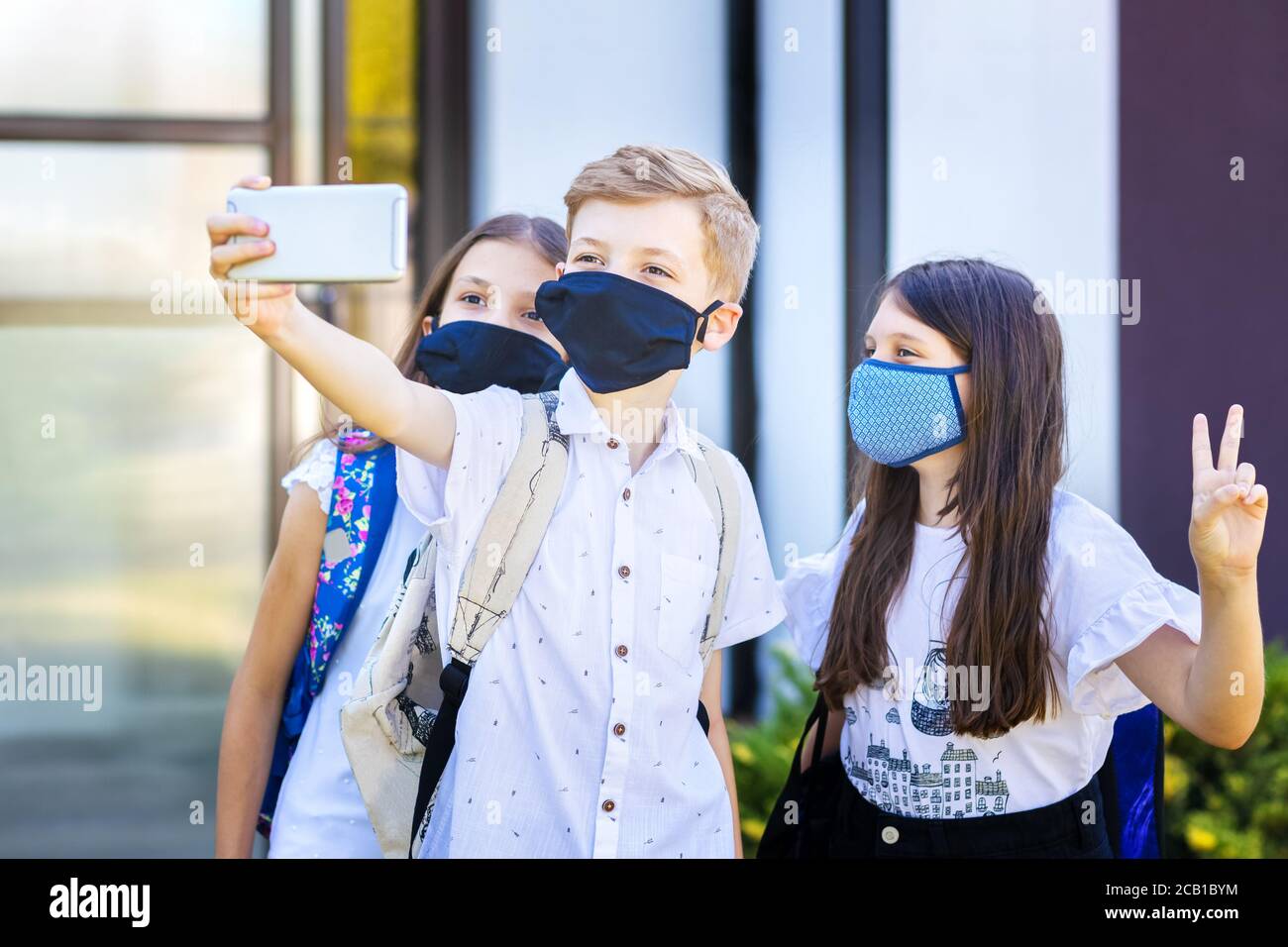 School children wearing protective face masks while taking selfie at school reopening Stock Photo