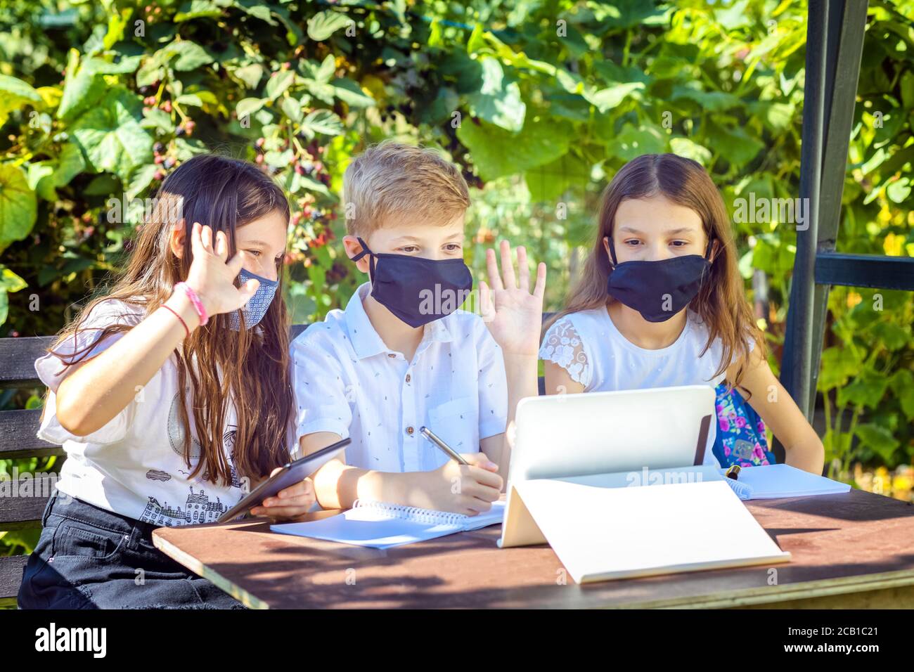 School children wearing protective face mask watching online education classes at home during corona virus lockdown outbreak Stock Photo