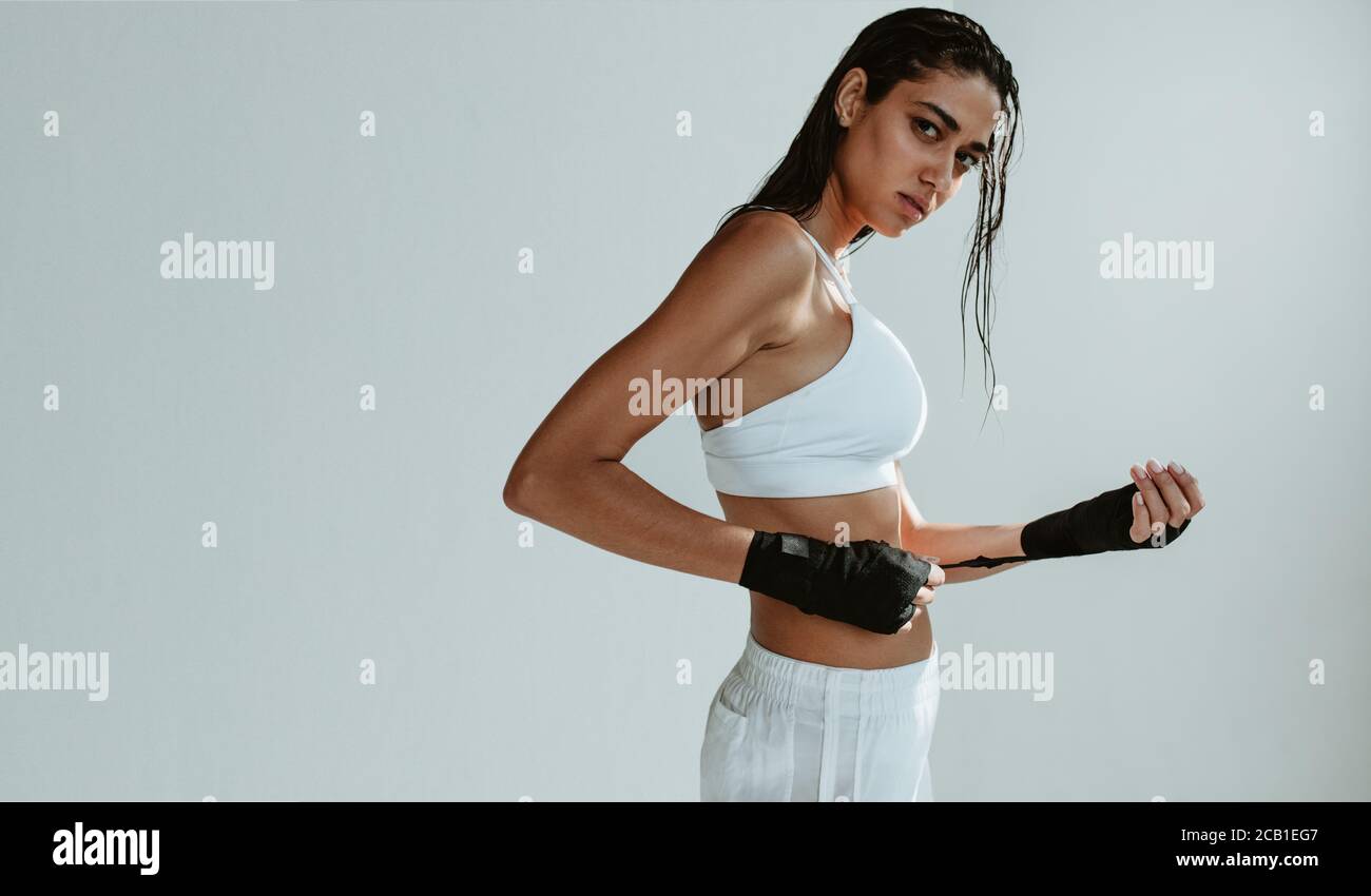 Healthy female boxer wearing boxing wraps. Muscular woman getting ready for boxing exercise