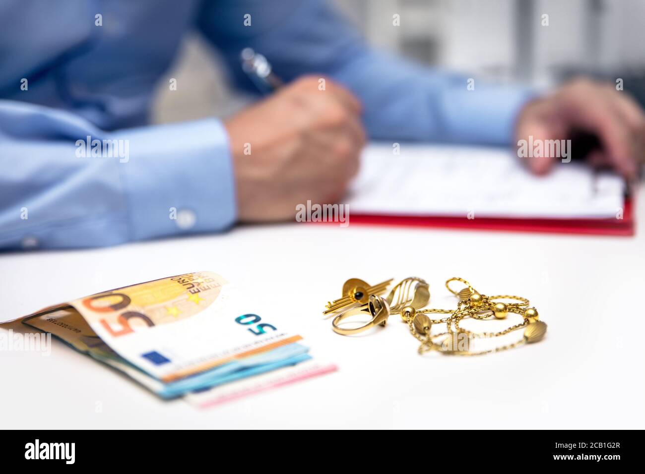 Businessman in the back, euro banknotes and gold jewellry in the front, disposal and selling Stock Photo