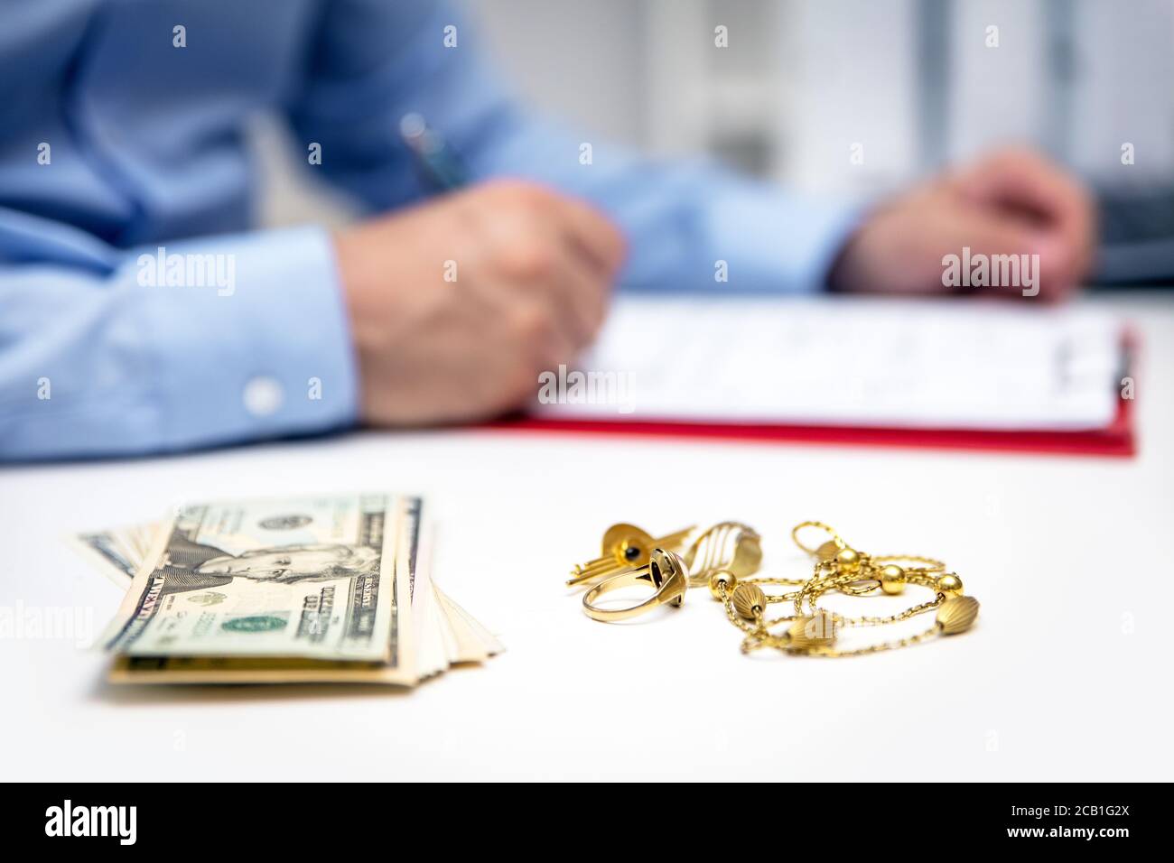 Businessman in the back, us dollars and gold jewellry in the front, disposal and selling Stock Photo