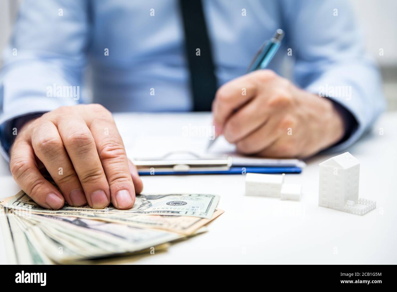 Businessman with us dollars and symbolic houses and building projects, bodypart hands Stock Photo