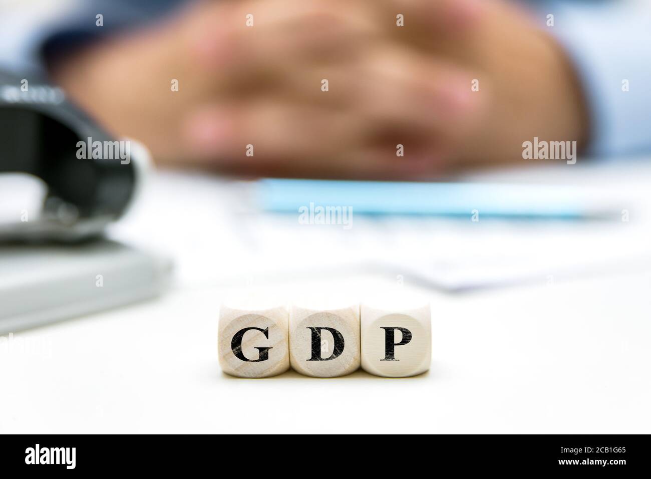 Office with man in the background, dice with word GDP, gross domestic product, english word Stock Photo