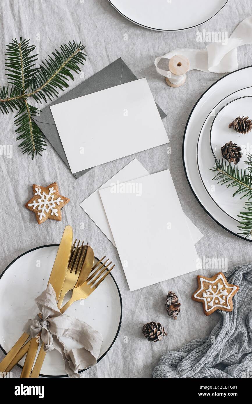 Christmas table setting. Blank greeting cards mockup scene. Golden cutlery,  green fir tree branches. Plates and gingerbread cookies, linen table cloth  Stock Photo - Alamy