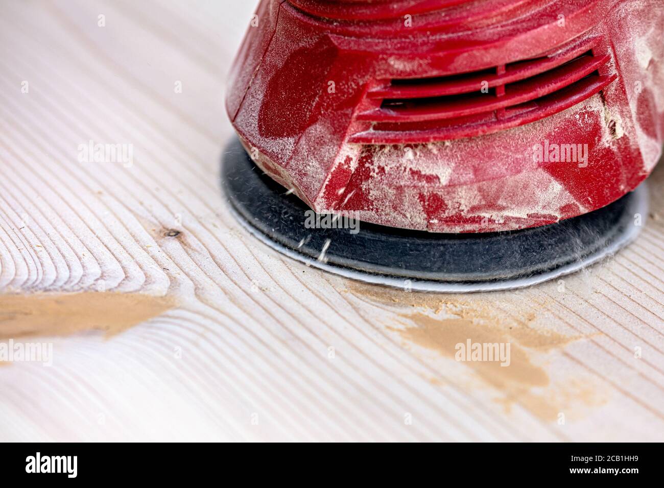 sanding a board with an random orbital sander or rotary sander, wooden board is filled with some paste Stock Photo