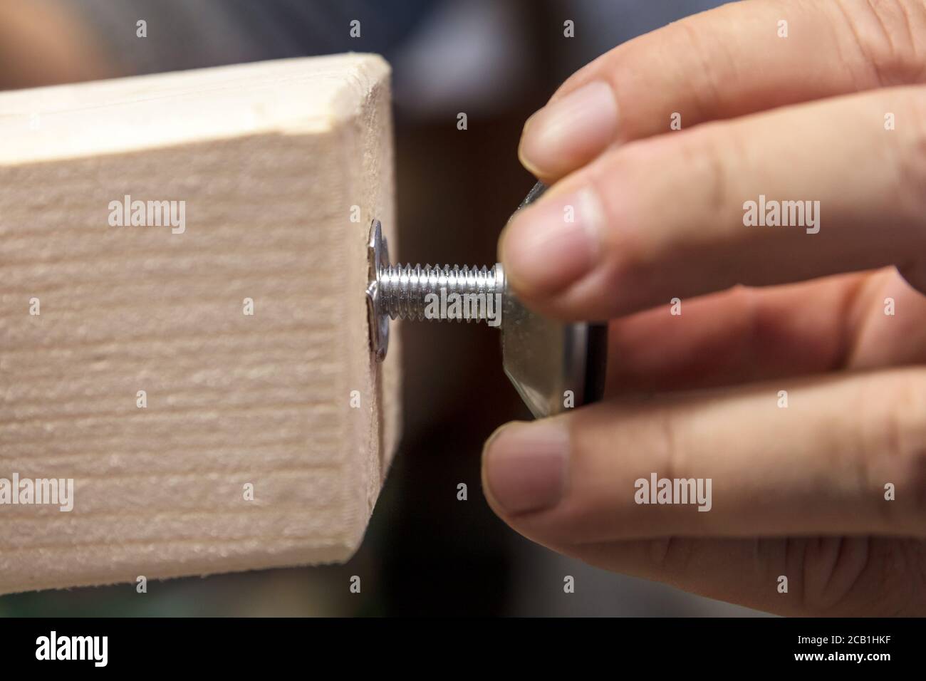 Man is installing a adjustable variable screw in a wooden desk or table leg Stock Photo