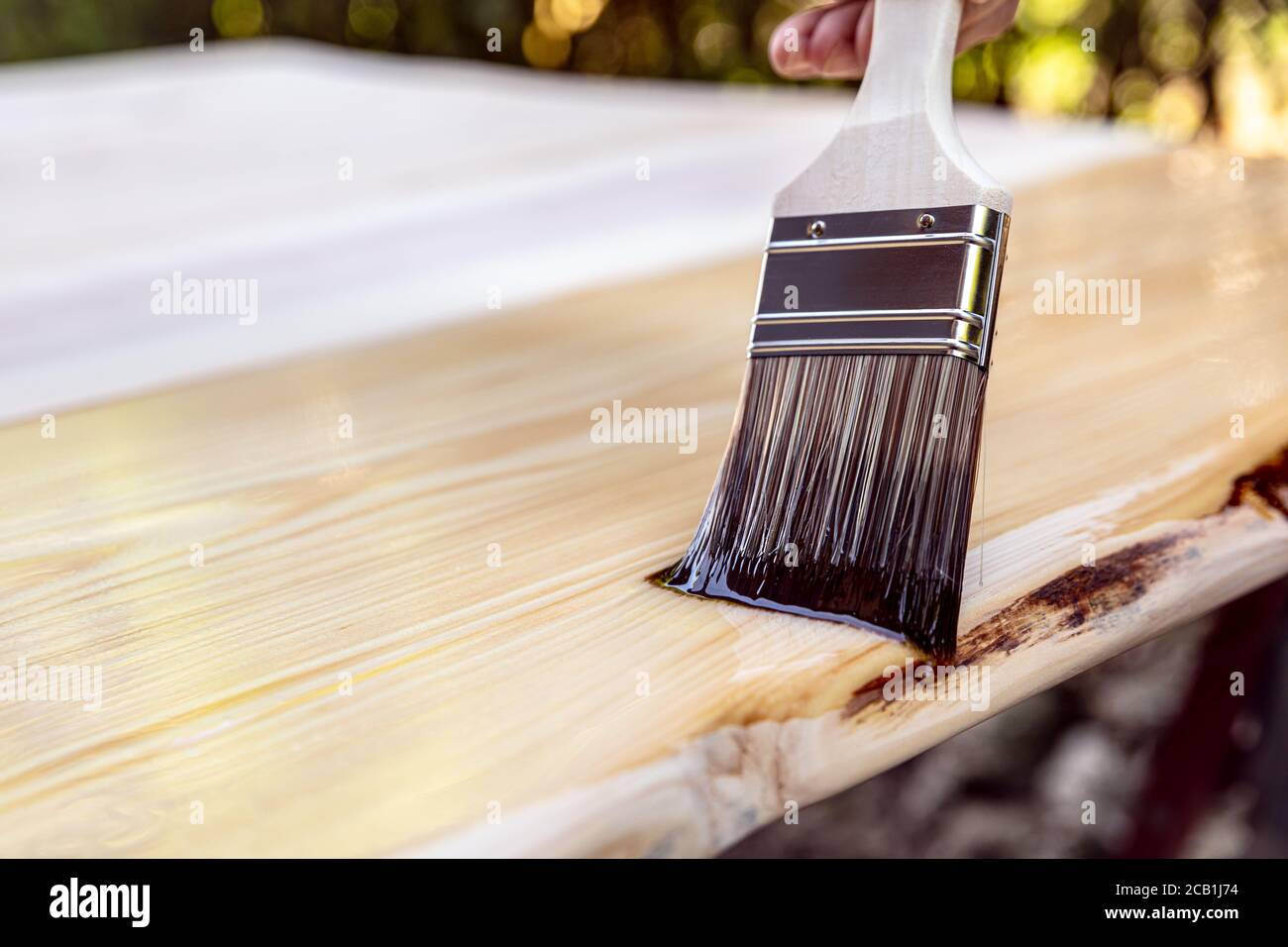outdoor glazing of a wooden table with a hair brush and oil, concept wood protection Stock Photo