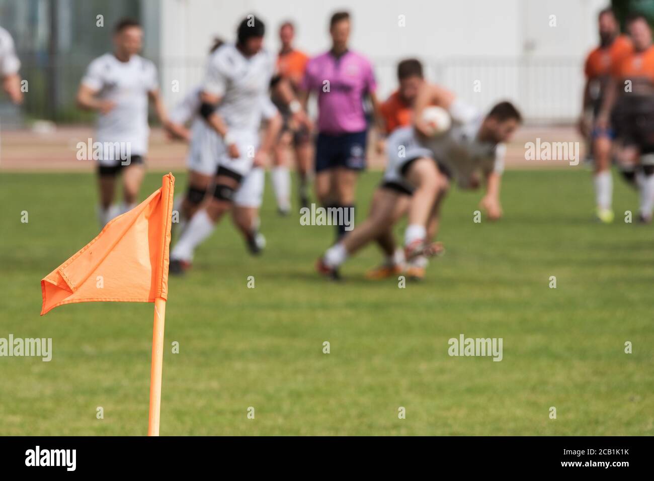 Flag on the pitch with rugby match in the background. Stock Photo