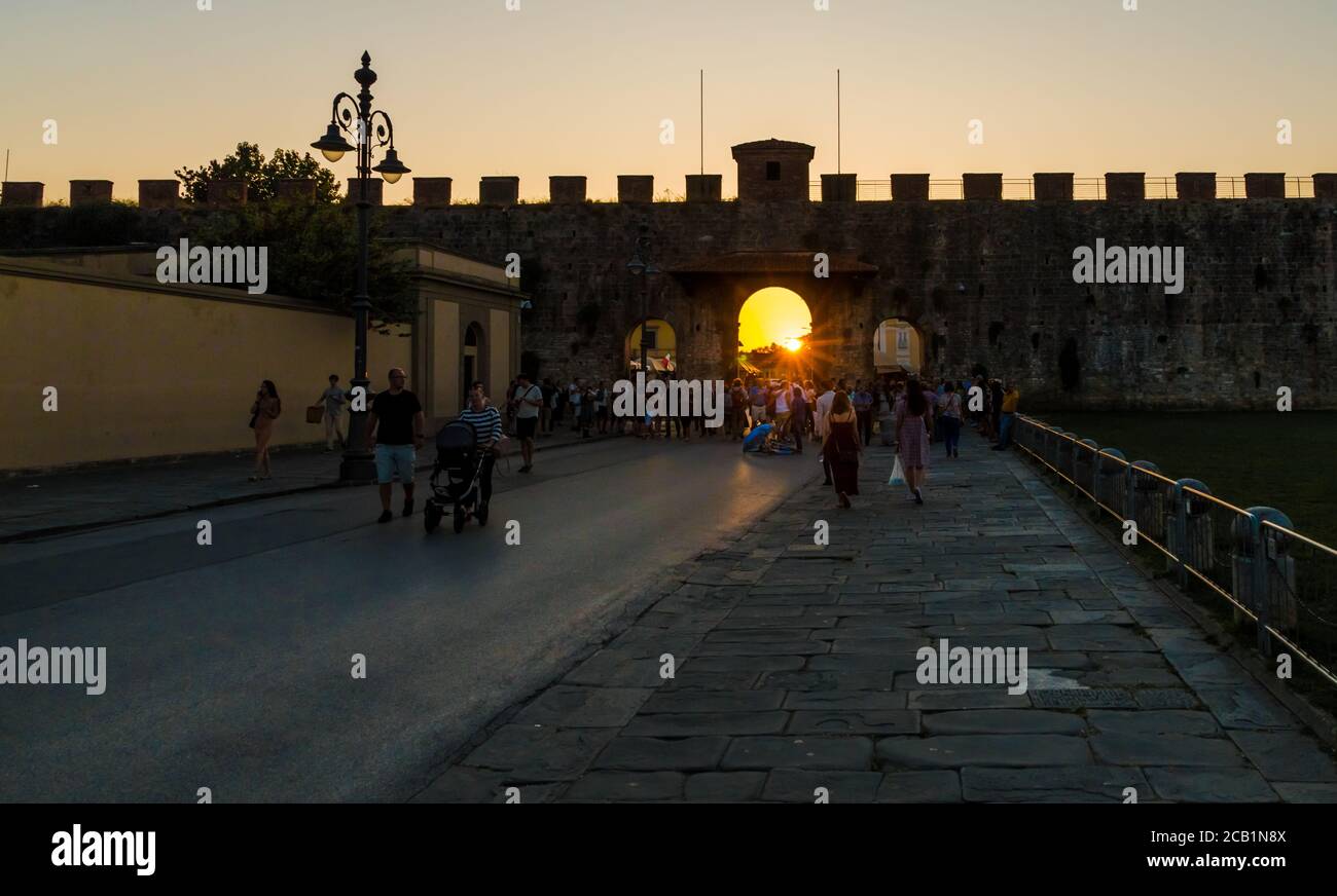Beautiful view of the medieval wall of the Piazza dei Miracoli in Pisa by sun set. Tourists gathering at the entrance of the famous square, an UNESCO... Stock Photo