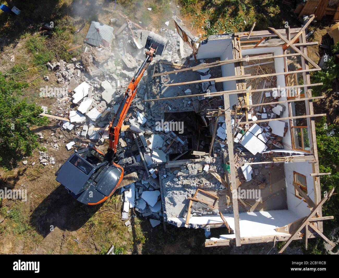 Destroying Old House Using Bucket Excavator in the village.  Demolish a. The destruction of the old house the excavator. Top view. Drone shot. Stock Photo