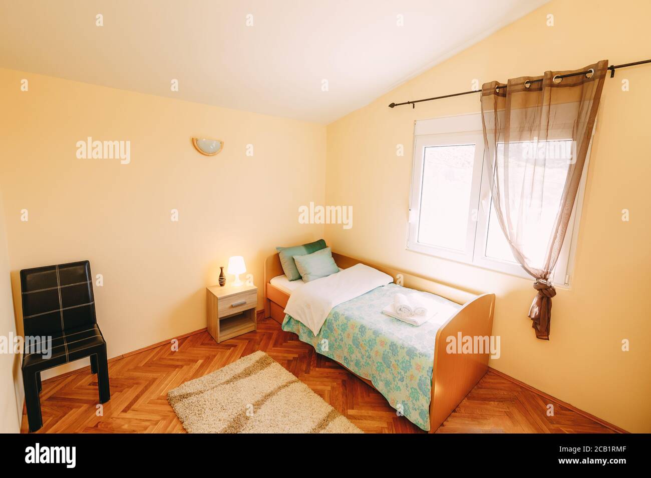 A Room With A Sloped Ceiling And A Plastic Window With A Bed With A Side Board A Chair And A Bedside Table In A Row Stock Photo Alamy