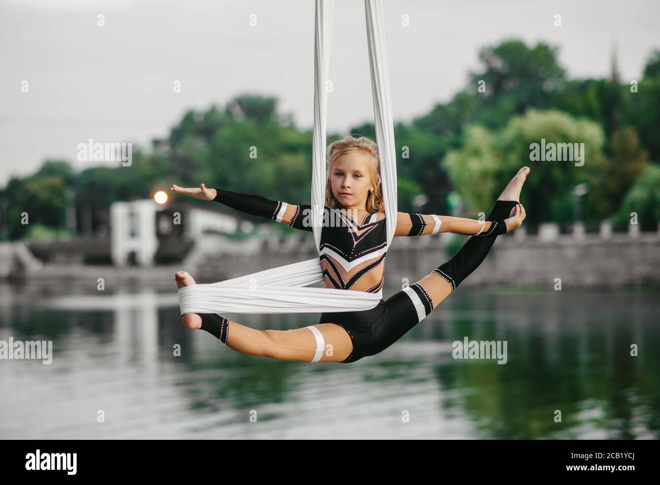 Child girl aerialist performs gymnastic split on hanging aerial