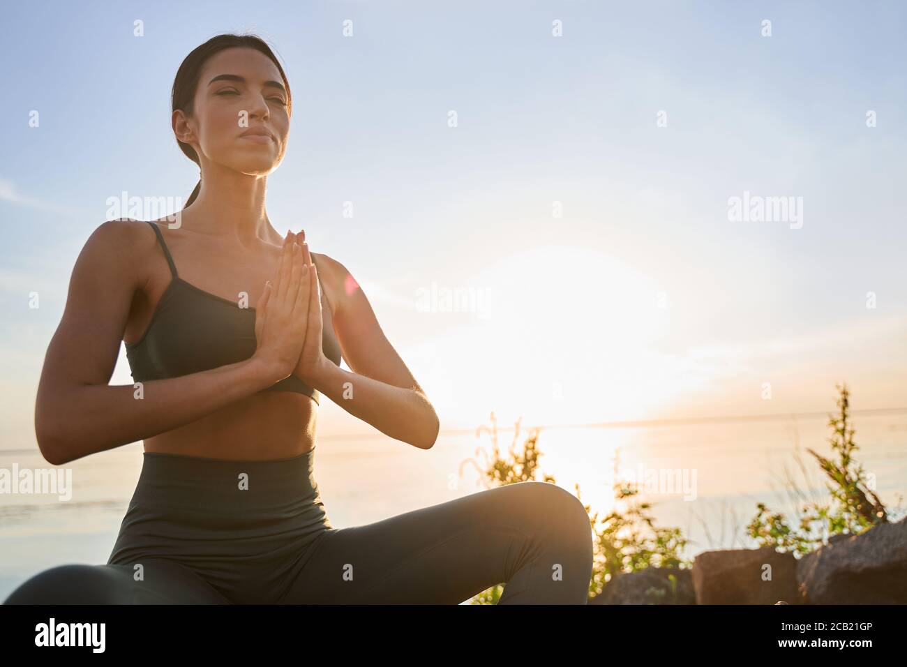 Charming young woman meditating on sunny day Stock Photo