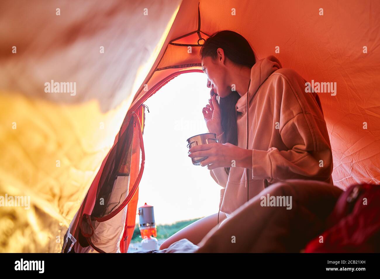 Beautiful young woman having breakfast in camp tent Stock Photo
