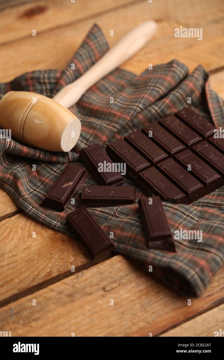 Vertical shot of a wooden small mallet near a bar of dark chocolate Stock Photo