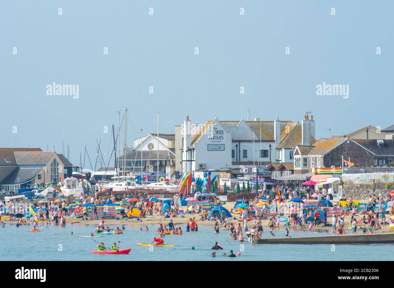Lyme Regis, Dorset, UK. 10th Aug, 2020. UK Weather: Holidaymakers, families and beachgoers bask in the hot and hazy sunshine on the beach at the seaside resort of Lyme Regis on what is set to be the last sunny day before thunderstorms and rain arrive later in the week. Credit: Celia McMahon/Alamy Live News Stock Photo